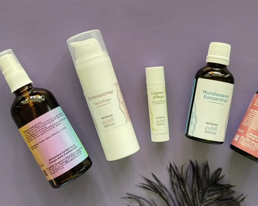 Etiketten für Natürlich g'scheit gepflegt: Melissen Hydrolat, Schmeichler Hautpflege, Lippenpflege und Mundwasser Konzentrat auf lila Hintergrund